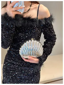 Elegant silver shell clutch bag held by model in a black sequined evening dress