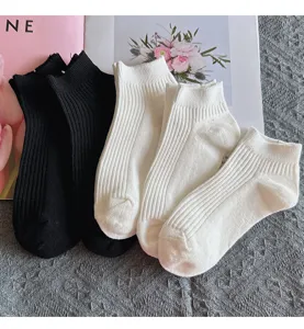 Detail view of solid color men low cut ribbed boat socks in classic black and white style.