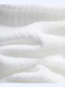 Close-up detail of pure white knitted cotton fabric texture showing soft and breathable material.