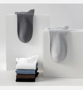Detailed view showing ribbed cotton men socks neatly stacked and draped on white display blocks.