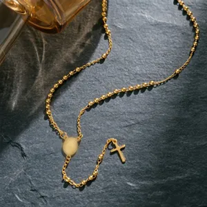 Dettaglio di una collana a rosario vintage in acciaio inossidabile dorato con croce