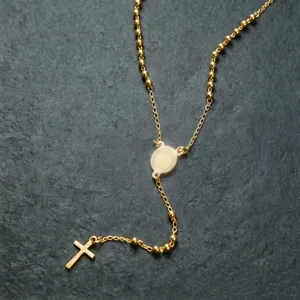 Dettaglio di una collana rosario in acciaio inossidabile dorato con medaglia e croce.