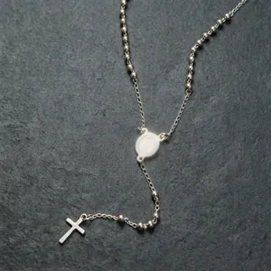 Primo piano di una collana rosario in acciaio inossidabile con croce su ardesia
