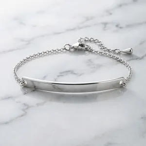 Detailed close-up of polished stainless steel curved bar bracelet on white marble surface