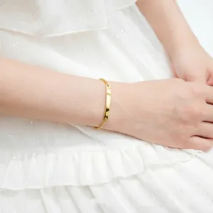 Elegant gold-tone stainless steel curved bar bracelet detail on a model's wrist