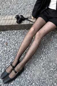 Close-up sheer black polka dot tights detail, showing ultra-thin sheer leg texture outdoors.
