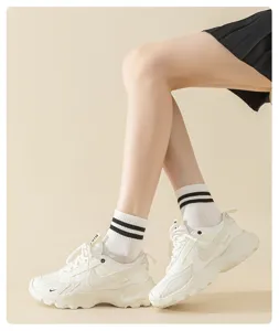 Detailed shot of classic black and white double stripe socks worn with stylish white sneakers.