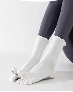 Gros plan de chaussettes d'orteils blanches à volants avec grips en silicone pour pilates.