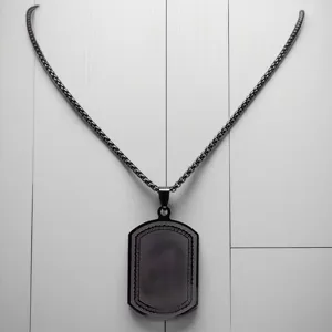 Macro detail of black stainless steel dog tag pendant with engraved border pattern