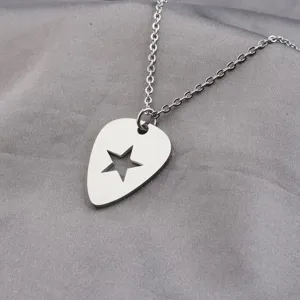 Close-up shot of a silver guitar pick necklace with a hollow star pendant on silk background