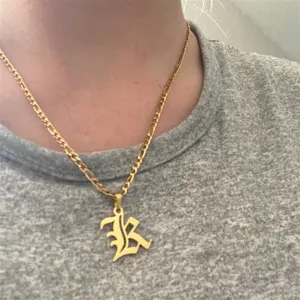 Detailed close-up view of a vintage gold Gothic initial K pendant necklace worn on a neck.