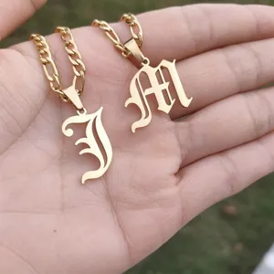 Close-up detail of gold stainless steel necklaces with Gothic J and M initial pendants