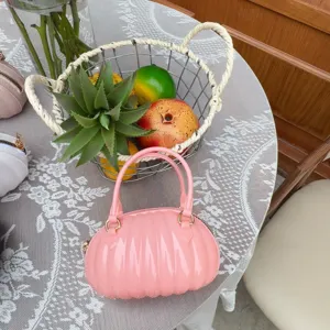 Vue détaillée d'un élégant sac à main en PVC rose en forme de citrouille sur une nappe.