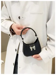 Macro view of a stylish black PVC jelly handbag with a silver bow and round handle.