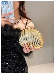 Elegant gold metallic shell shaped evening bag held by a model in a black dress