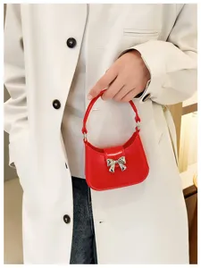 Red PVC jelly handbag with silver bow detail held by hand against a stylish coat