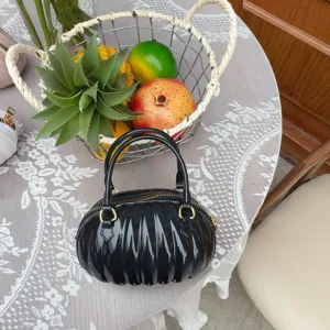 Vue détaillée d'un sac à main noir en PVC en forme de citrouille sur table en dentelle