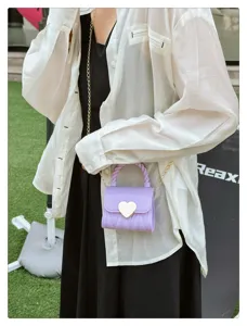 Purple mini PVC jelly bag with gold heart lock and chain strap carried by a model