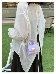Detailed view of a purple PVC jelly mini bag with a golden heart lock on a model