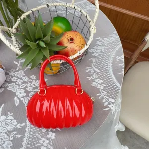Vue détaillée d'un sac à main en PVC rouge brillant avec un design de citrouille.
