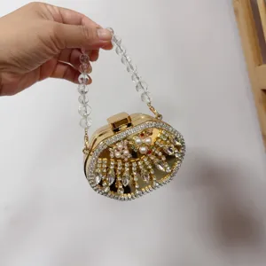Detail view of gold evening clutch bag with crystals, pearls, and clear beaded handle