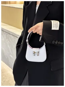 Close-up of a chic white PVC jelly handbag featuring a metallic silver bow detail.