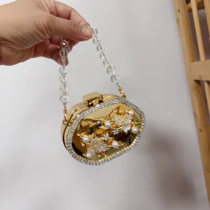 Detailed view of a gold floral metal clutch with pearls and crystal handle