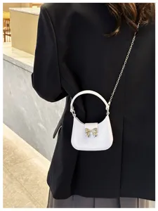 Detail of mini lavender jelly bag with gold bow and chain strap on black blazer
