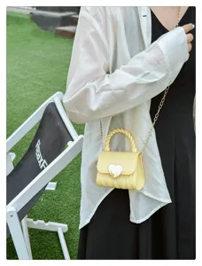 Close-up detail of stylish yellow mini PVC jelly bag with heart lock and chain strap