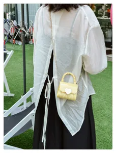 Small yellow PVC jelly bag with heart buckle and chain strap on a model outdoors.