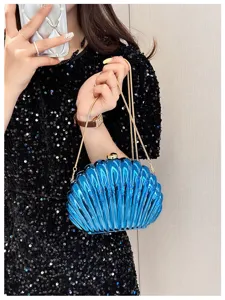 Close-up of blue candy-colored shell-shaped evening clutch bag with gold chain strap.