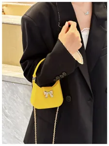 Close-up detail of a vibrant yellow PVC jelly bag featuring a bow and gold chain strap