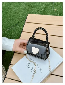 Detail of mini black PVC jelly bag with white heart clasp and gold chain strap