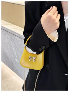 Yellow jelly PVC handbag with silver bow detail and chain strap worn by model