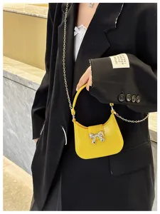 Modern yellow PVC jelly mini bag featuring a silver bow accent and slim chain strap