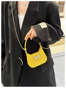 Close-up detail of a bright yellow jelly bag featuring a silver bow and gold chain.
