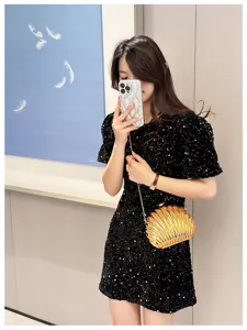 Elegant gold shell-shaped evening clutch bag with chain strap worn by a model in black