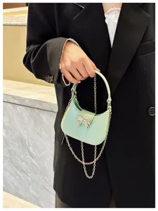 Close-up view of a stylish mint green bow jelly handbag with an elegant gold chain strap