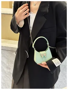 Mini mint green jelly bag with bow detail and gold chain strap held by model