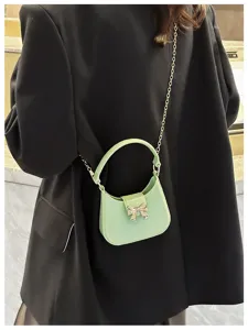 Close-up of mint green jelly bag with silver bow and gold chain strap