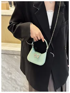 Close-up detail of a mint green PVC jelly bag featuring a silver bow and metal chain strap