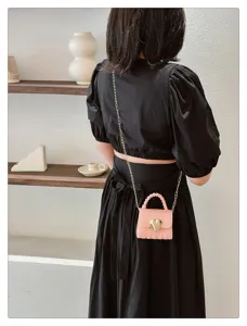 Lifestyle detail showing a pink mini heart jelly crossbody bag with gold chain strap
