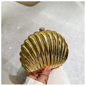 Macro view of a gold shell-shaped evening bag with metallic finish and chain strap