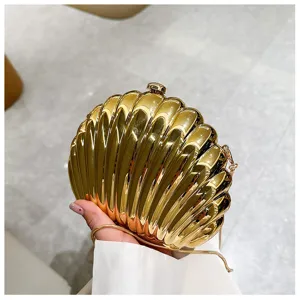 Detail of golden shell-shaped evening bag with metallic finish and delicate chain strap.