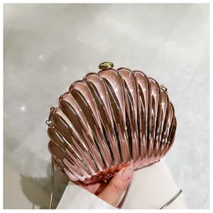 Close-up of a glossy rose gold shell-shaped evening clutch bag with chain strap