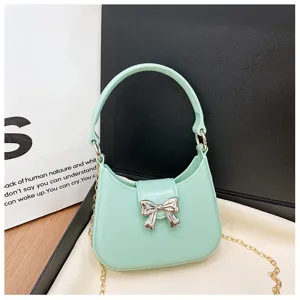Close-up of mint green PVC jelly bag featuring silver bow detail and gold chain strap