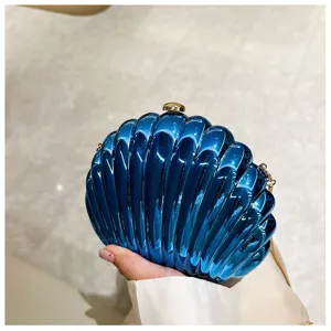 Close-up of a stylish blue shell-shaped evening clutch bag with gold chain strap
