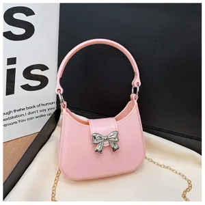 Close-up detail of a stylish pink PVC jelly bag with a silver bow and gold chain strap.