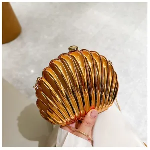 Detailed macro view of a shiny metallic orange shell-shaped evening clutch bag with chain