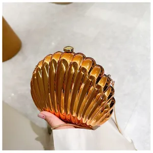 Elegant metallic gold shell-shaped evening clutch bag with a delicate chain strap held by hand.